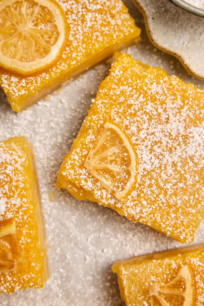 Delicious lemon bars topped with powdered sugar and lemon slices, perfect for sweet citrus dessert lovers.