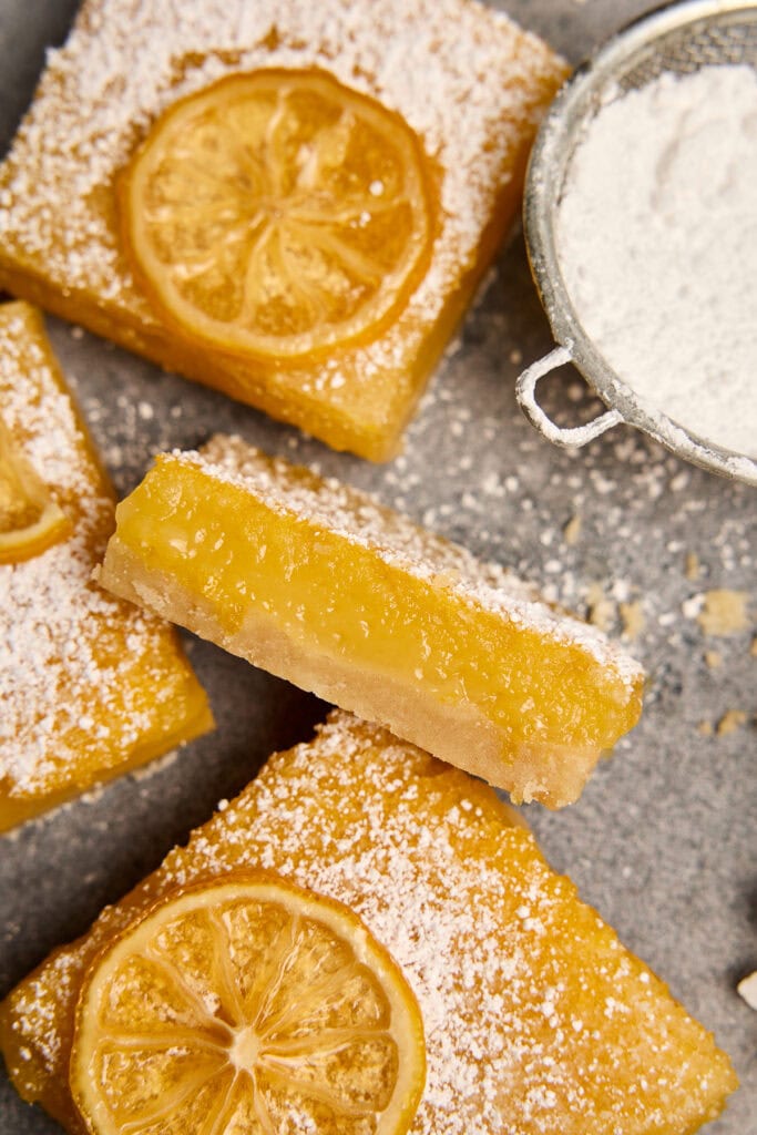 Delicious lemon bars topped with powdered sugar and fresh lemon slices, perfect for sweet cravings and dessert lovers.