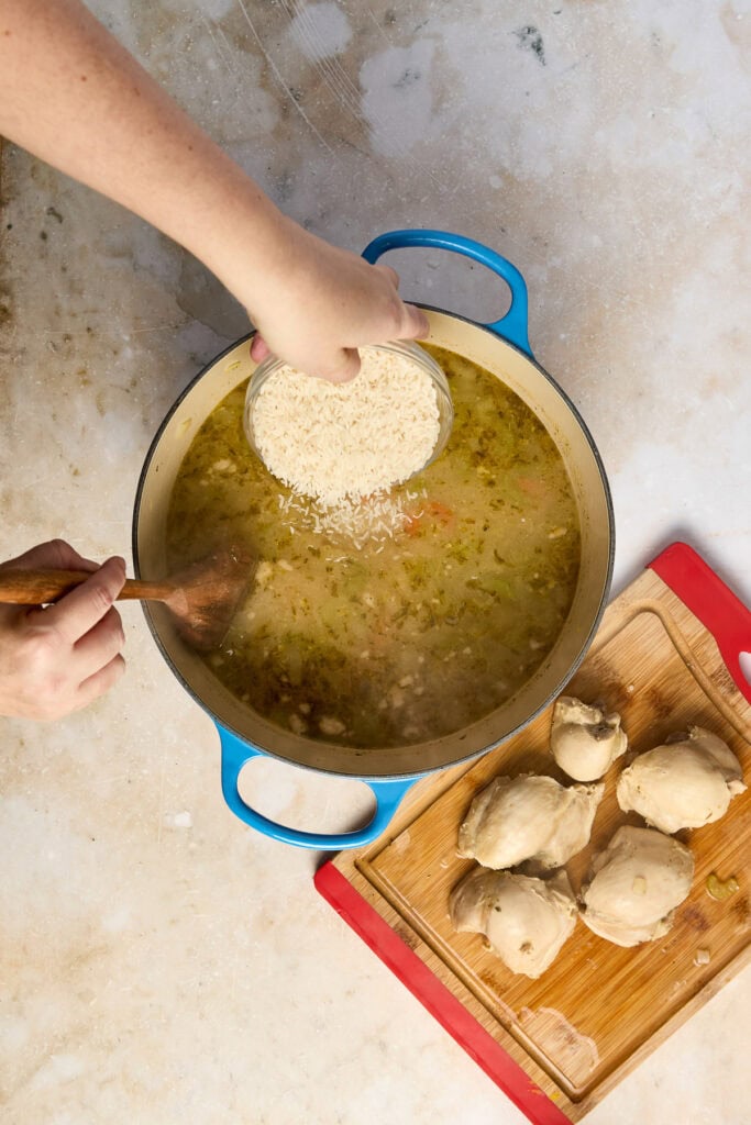Preparing lemon chicken rice soup with fresh ingredients, including chicken, rice, and lemon, in a cozy kitchen setting.