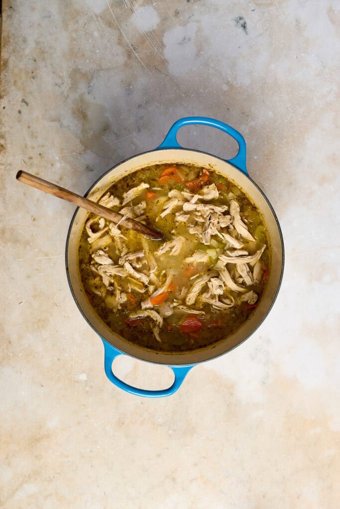 Delicious lemon chicken rice soup in a blue pot, featuring shredded chicken, rice, and vegetables in a flavorful broth, perfect for comforting meals.