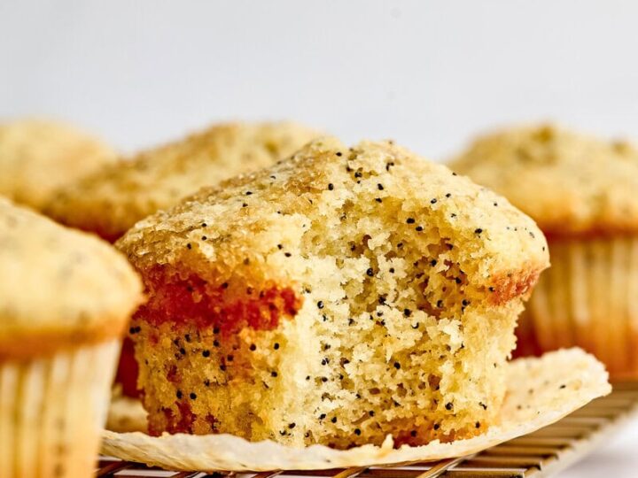 Freshly baked lemon poppy seed muffin on a cooling rack, showcasing a golden crust and moist interior with visible poppy seeds, perfect for breakfast or snack.