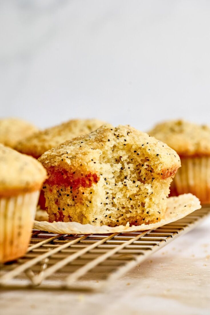Freshly baked lemon poppy seed muffin on a cooling rack, showcasing a golden crust and moist interior with visible poppy seeds, perfect for breakfast or snack.