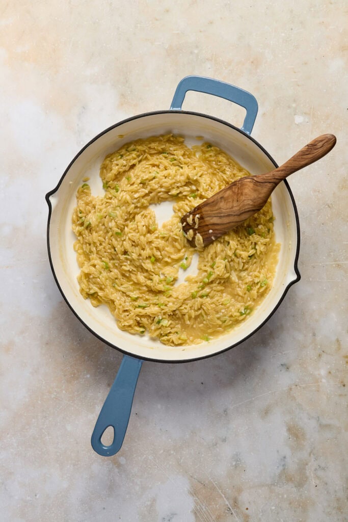 Delicious creamy spinach dip in a skillet, perfect for snacks, parties, or appetizers, served with a wooden spoon on a neutral background.