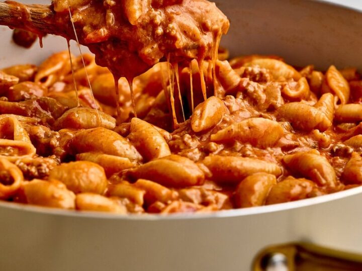 Close-up of a ground beef taco pasta with melted cheese in a white skillet, showcasing a hearty and flavorful comfort food dish.