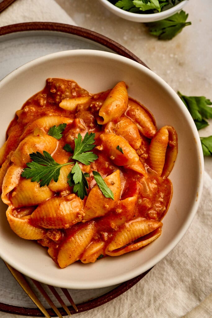 Delicious shell pasta in a rich tomato sauce garnished with fresh parsley, perfect for comforting meals and family dinners.