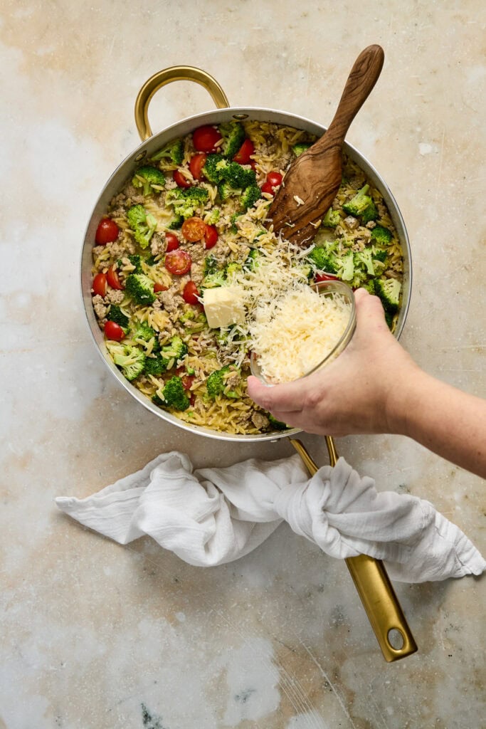 Healthy vegetable pasta salad with cheese, cherry tomatoes, and fresh greens in a skillet for a nutritious meal.