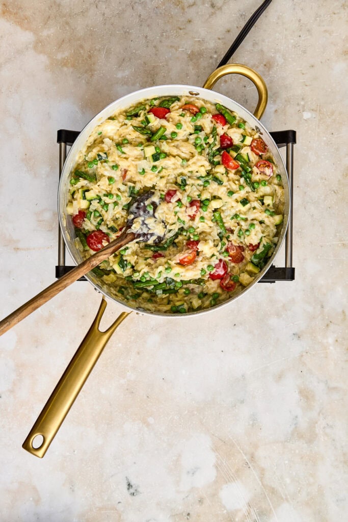 Delicious creamy chicken and rice casserole with fresh vegetables, herbs, and melted cheese, served in a golden skillet for a comforting meal.
