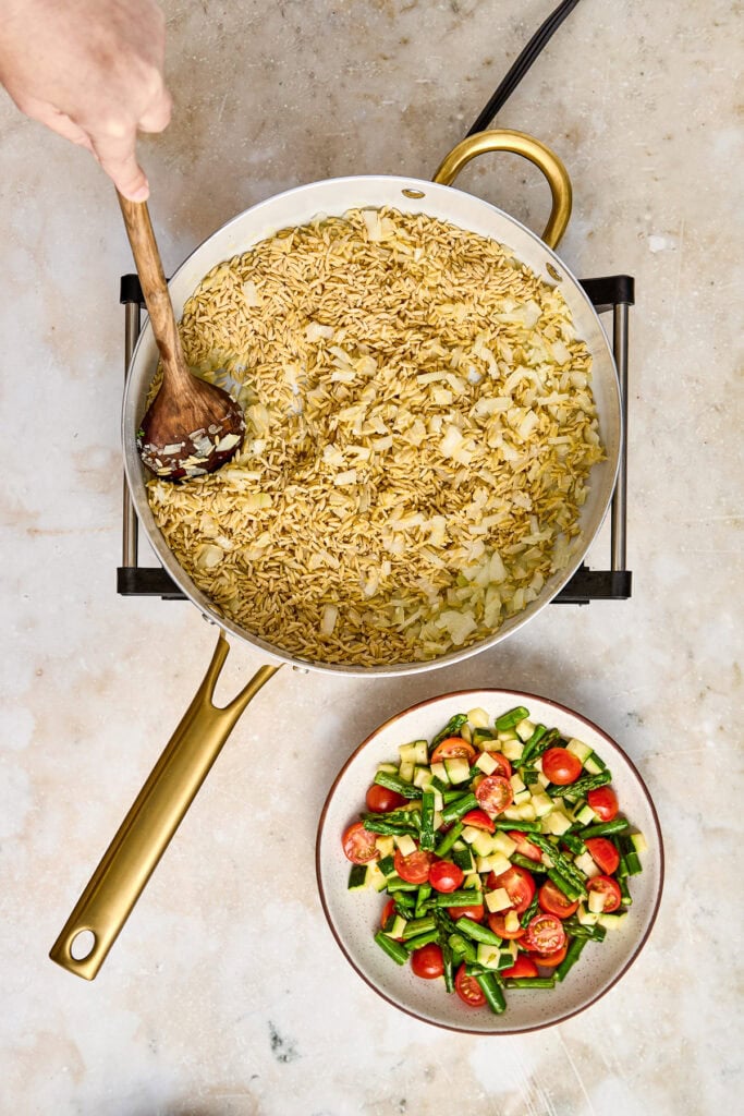 Cooking creamy chicken and rice in a skillet with a wooden spoon, served alongside a fresh vegetable salad with cherry tomatoes and cucumbers.