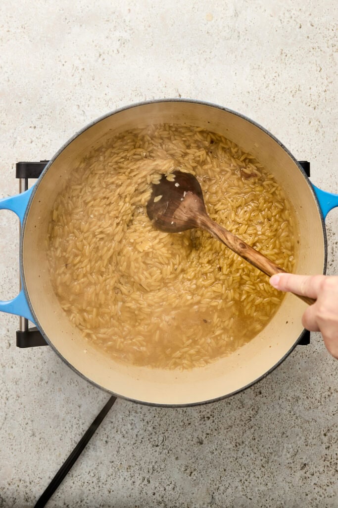 Cooking creamy pasta in a large blue pot with a wooden spoon, on a light-colored countertop, showcasing a delicious and comforting homemade meal.