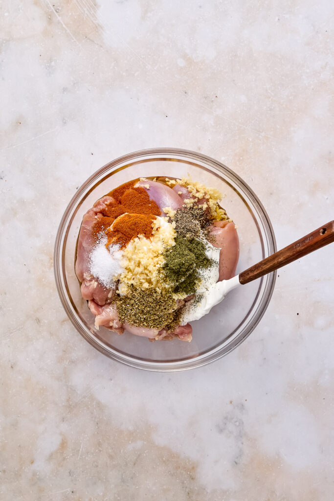 marinated chicken in greek yogurt in a bowl on a white background