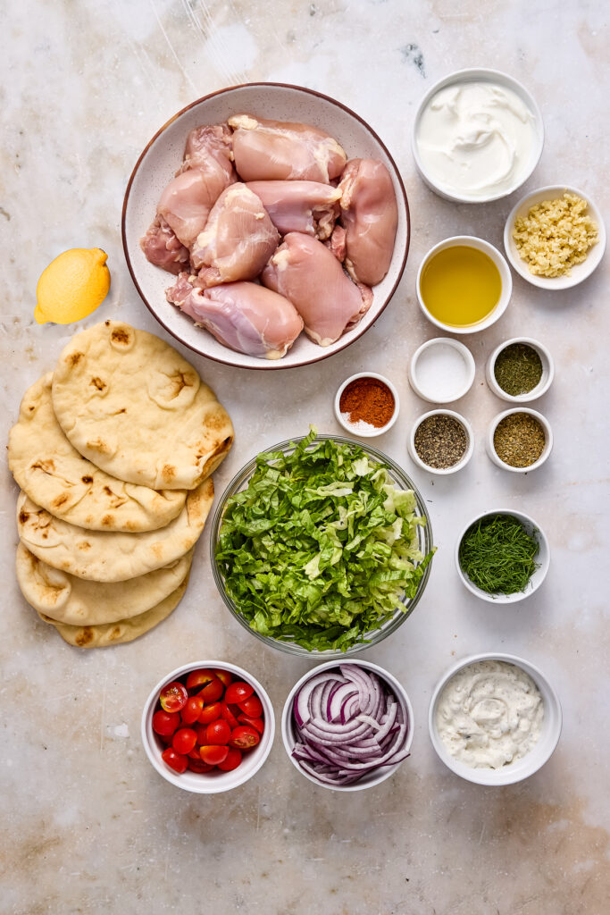 ingredients for greek chicken pitas on a gray background