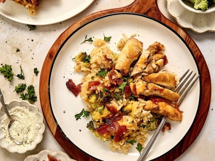 Delicious chicken bacon ranch rice casserole dish served with bacon, broccoli, and bread on a rustic table, perfect for a hearty meal.