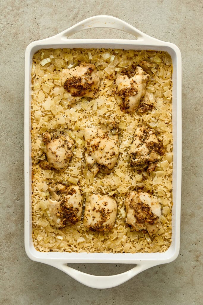 Baked chicken and rice casserole topped with crispy breadcrumbs, served in a white baking dish on a neutral surface.