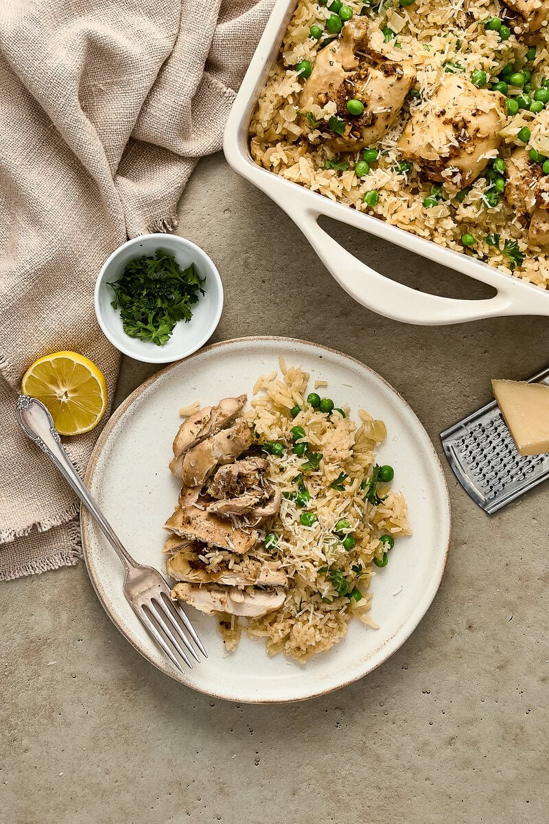 Tokyo Delicious chicken and rice casserole served on a white plate with fresh herbs, lemon, and grated cheese, perfect for family dinner.