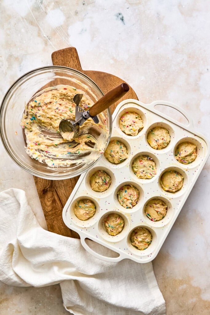 Baking homemade birthday cake mini muffin bites in a silicone mold with colorful sprinkles, ready to be baked or chilled for a sweet treat.