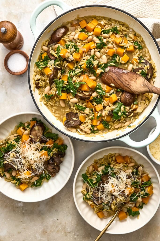 Delicious creamy butternut squash orzo with mushrooms, kale, and cheese served in a white bowl, perfect for a cozy meal.