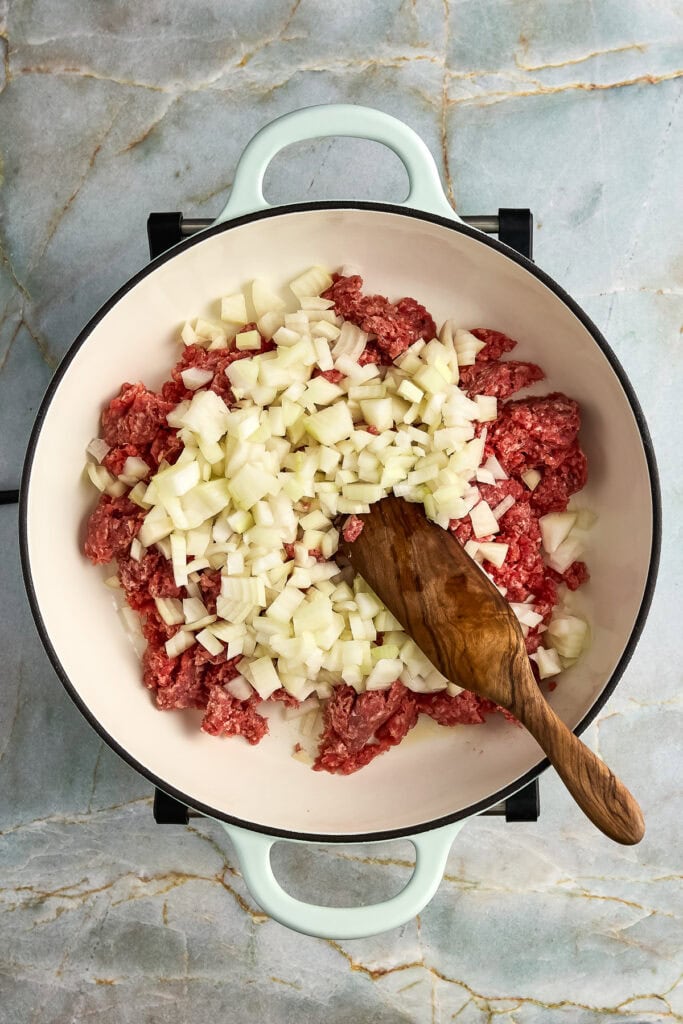 Ground beef and diced onion in a Dutch oven before browning