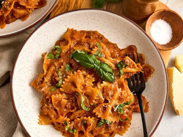 Bowl of creamy tomato ricotta pasta with ground beef, bowties and fresh basil