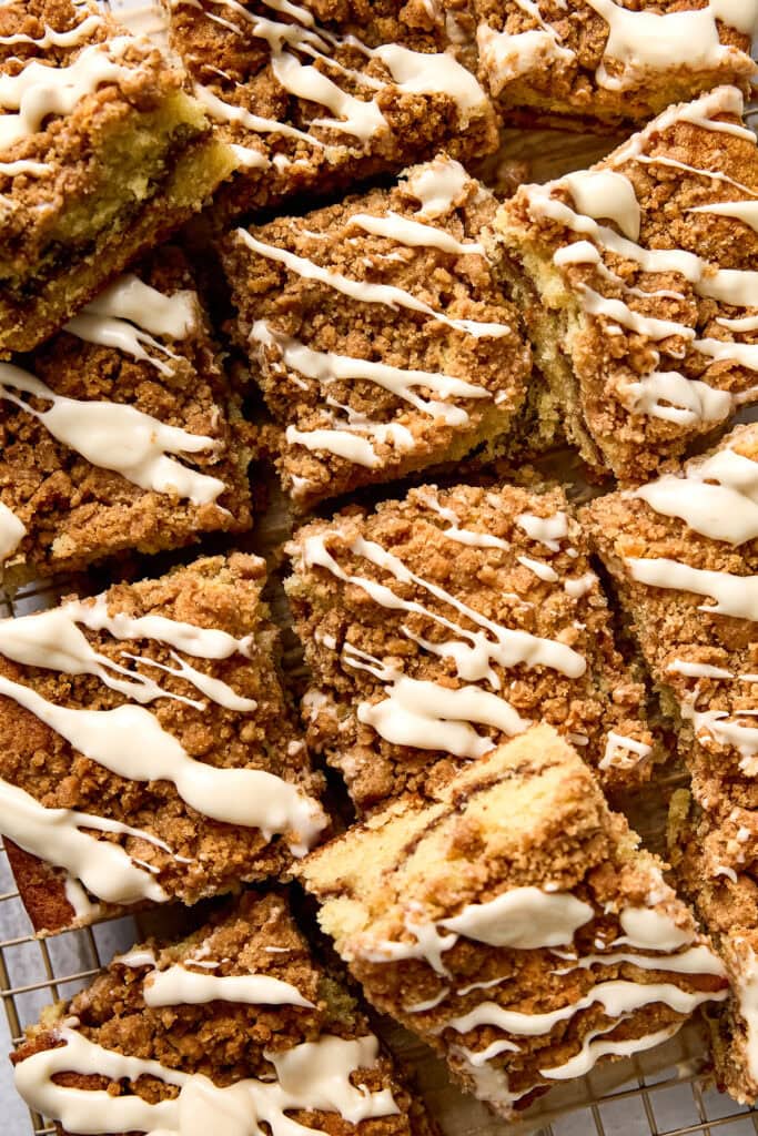 Close-up of slices of cinnamon coffee cake drizzled with white icing, showing a crumb streusel topping