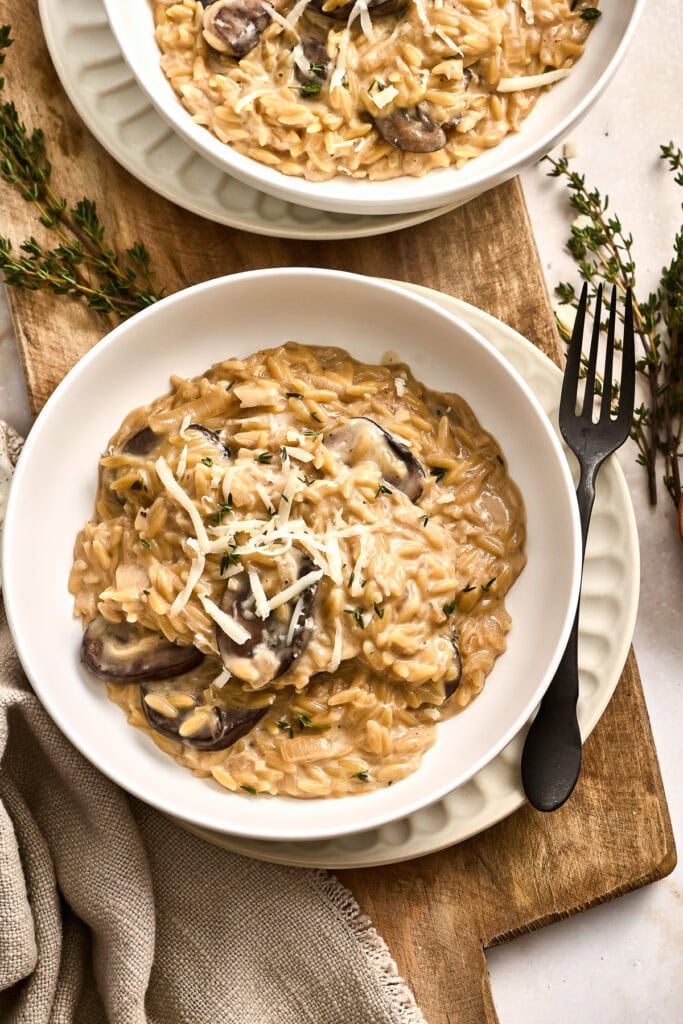 Delicious French onion pasta served in a white bowl with grated cheese and herbs, perfect for a comforting meal.