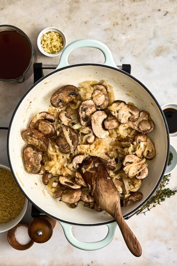 mushrooms and caramelized onions cooking in a skillet with garlic, herbs, and cheese, served with side dishes and fresh herbs.